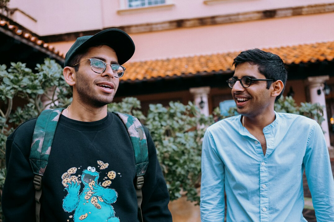 Two Mexican developers collaborating on insurance software code on a laptop